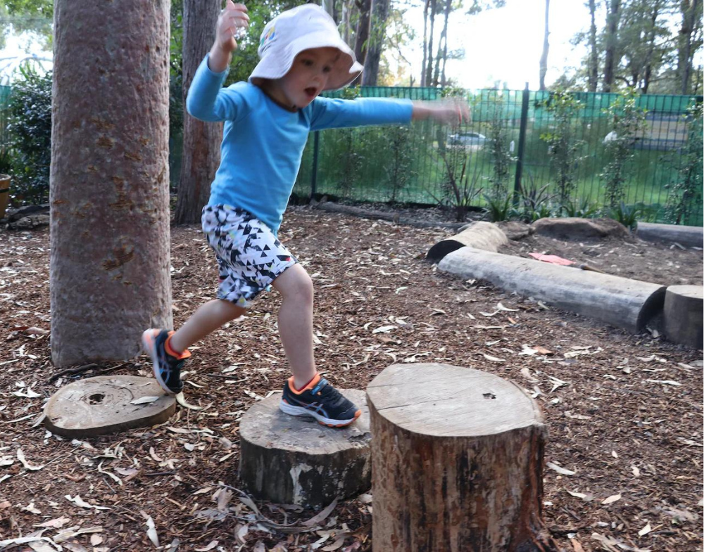 Child jumping on tree stumps