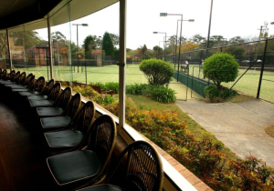 row of chairs inside in front of grass tennis courts
